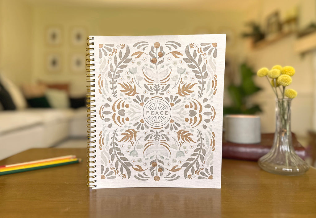 Notebook with decorative cover featuring the word 'Peace' on a blurred indoor background