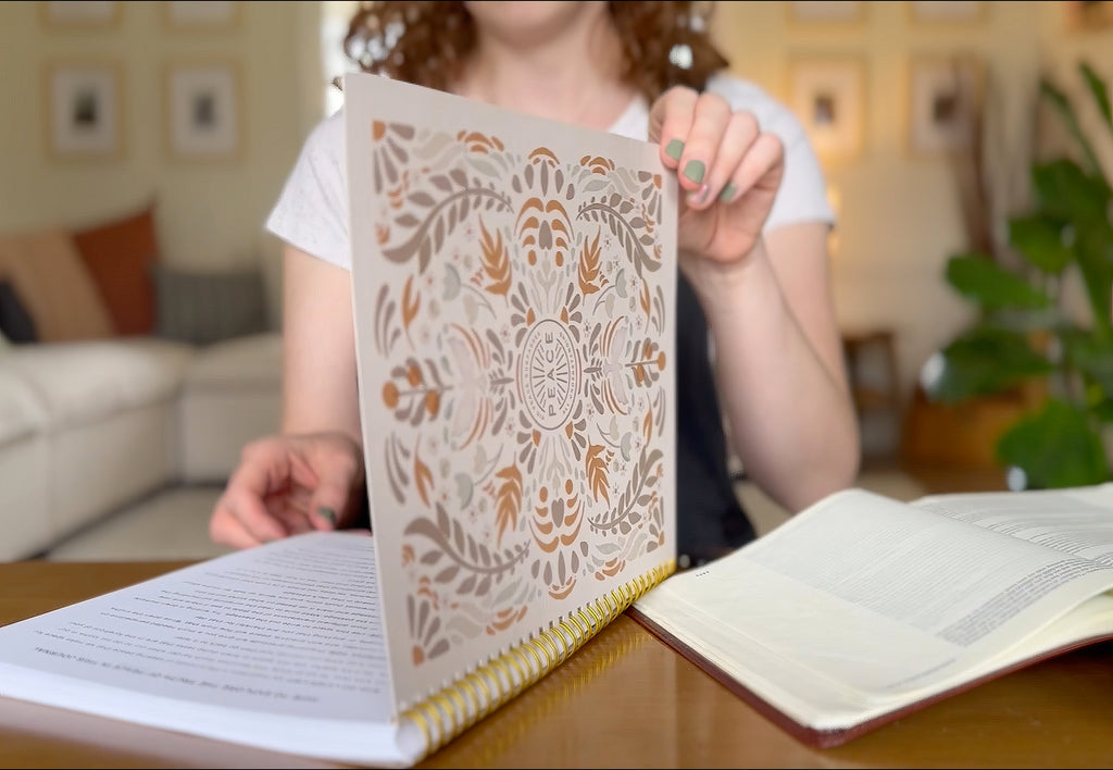 Person holding a decorative book with intricate patterns in a living room setting