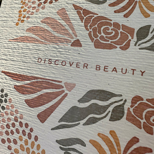 Textured paper with floral and abstract designs and 'DISCOVER BEAUTY' text.