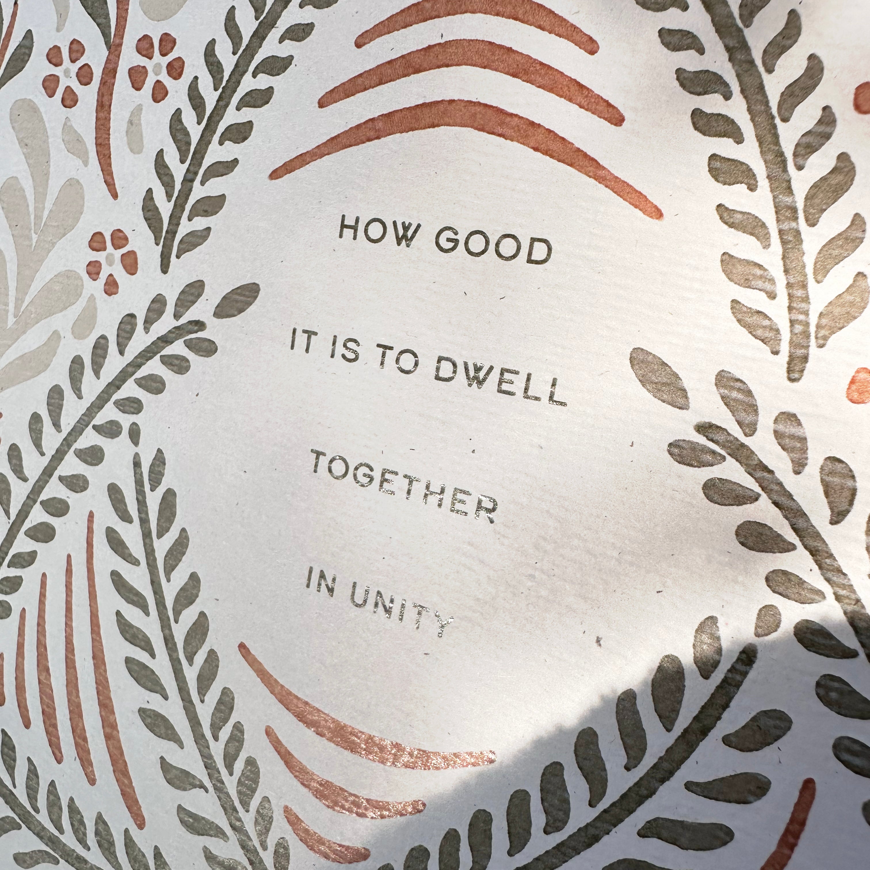 Decorative plate with floral patterns and text 'HOW GOOD IT IS TO Dwell TOGETHER IN UNITY' on a white background.