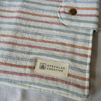 Close up of striped fabric pouch with a Speckled Creative label on a neutral background