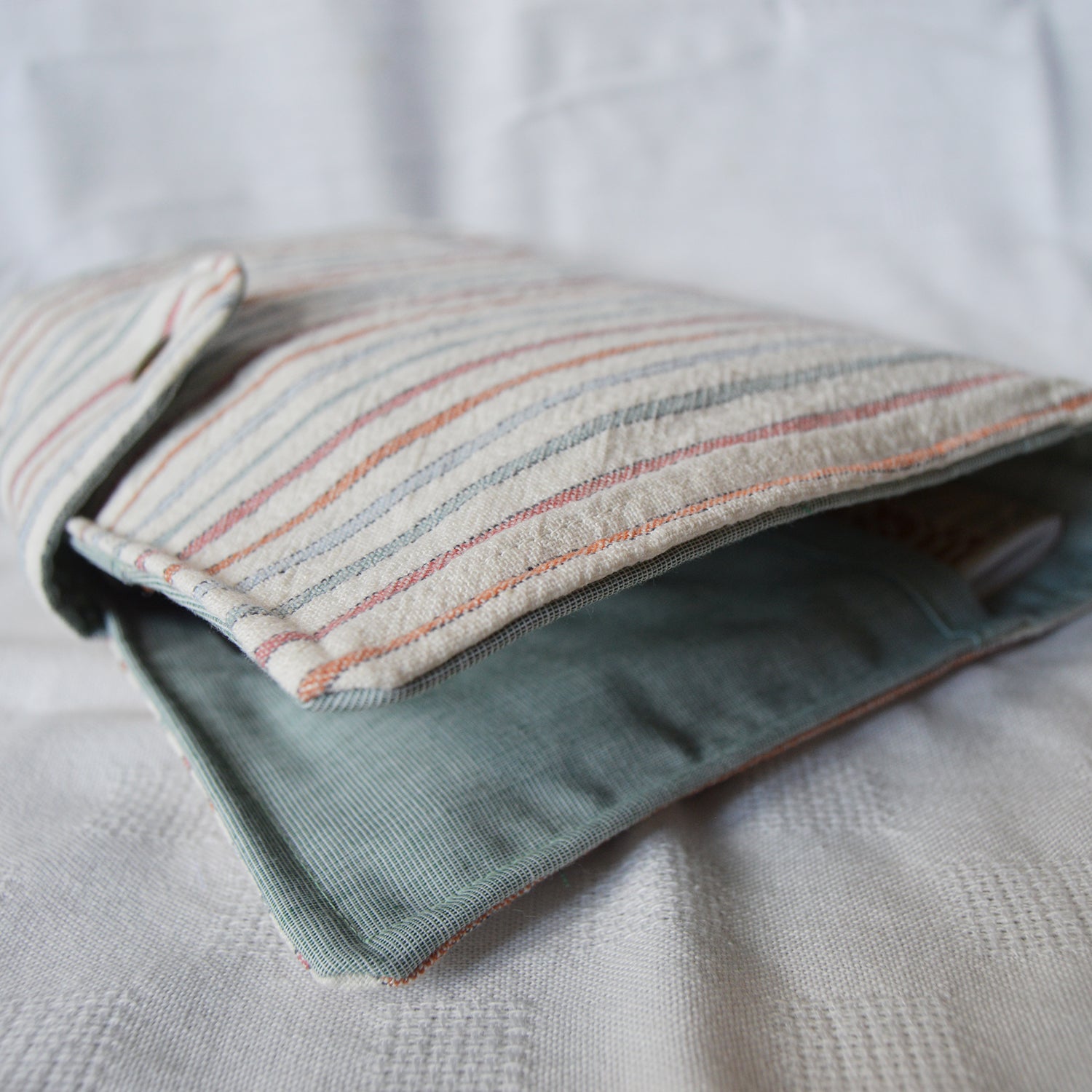 Folded fabric pouch with striped pattern on a textured surface