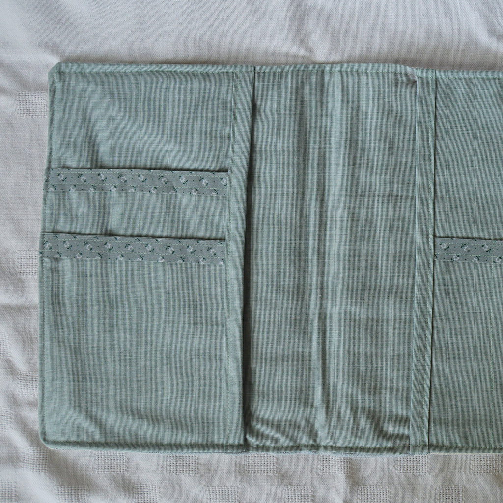 Interior teal fabric pouch with floral accents on a white background