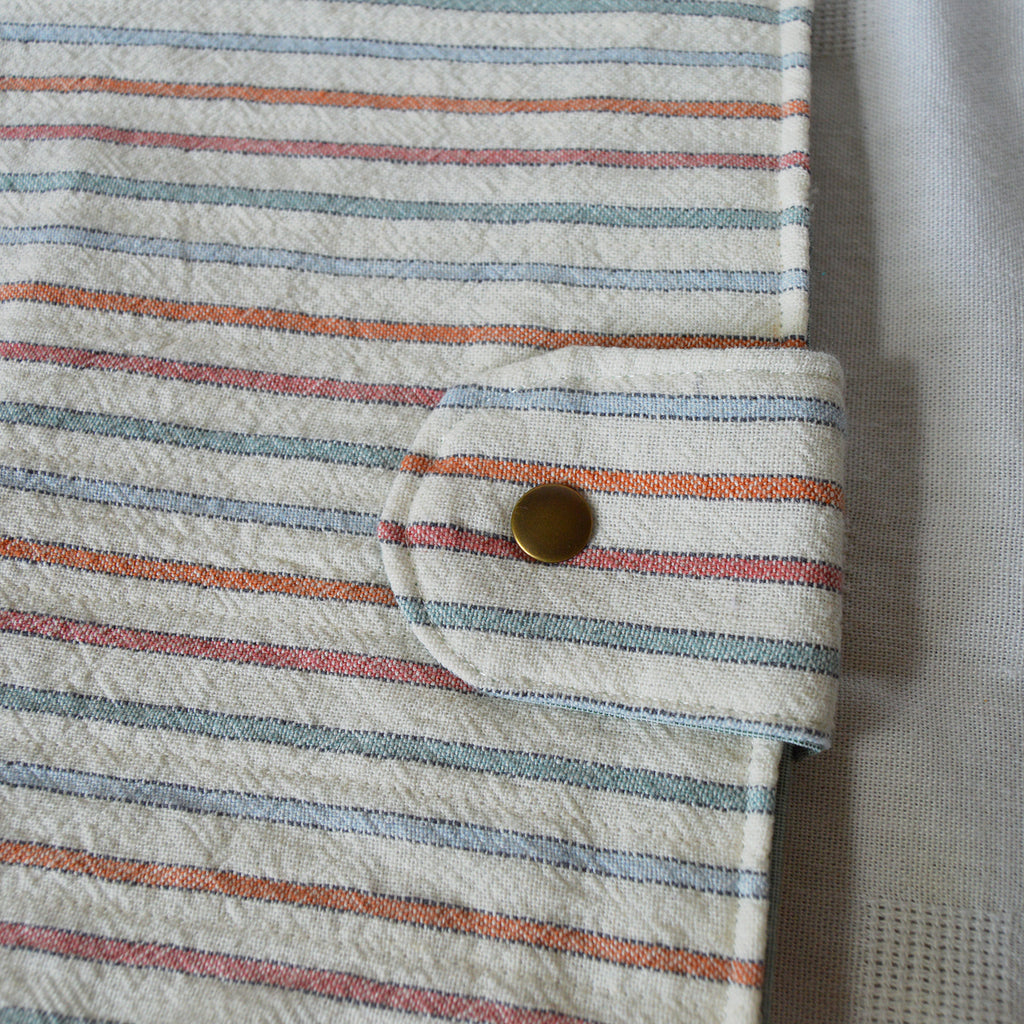 Close-up of a striped fabric pouch with a button, on a light background