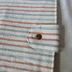 Close-up of a striped fabric pouch with a button, on a light background