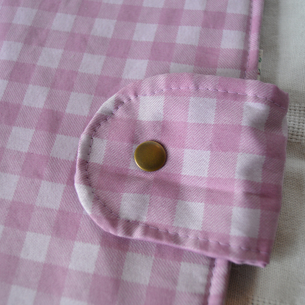 Close-up of a purple checkered fabric with a button on a textured background
