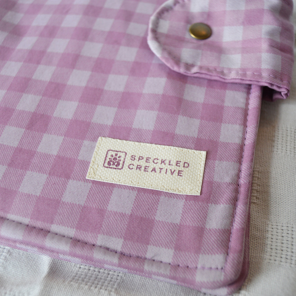 Purple and white checkered fabric with a brand label on a neutral background