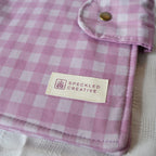Purple and white checkered fabric with a brand label on a neutral background