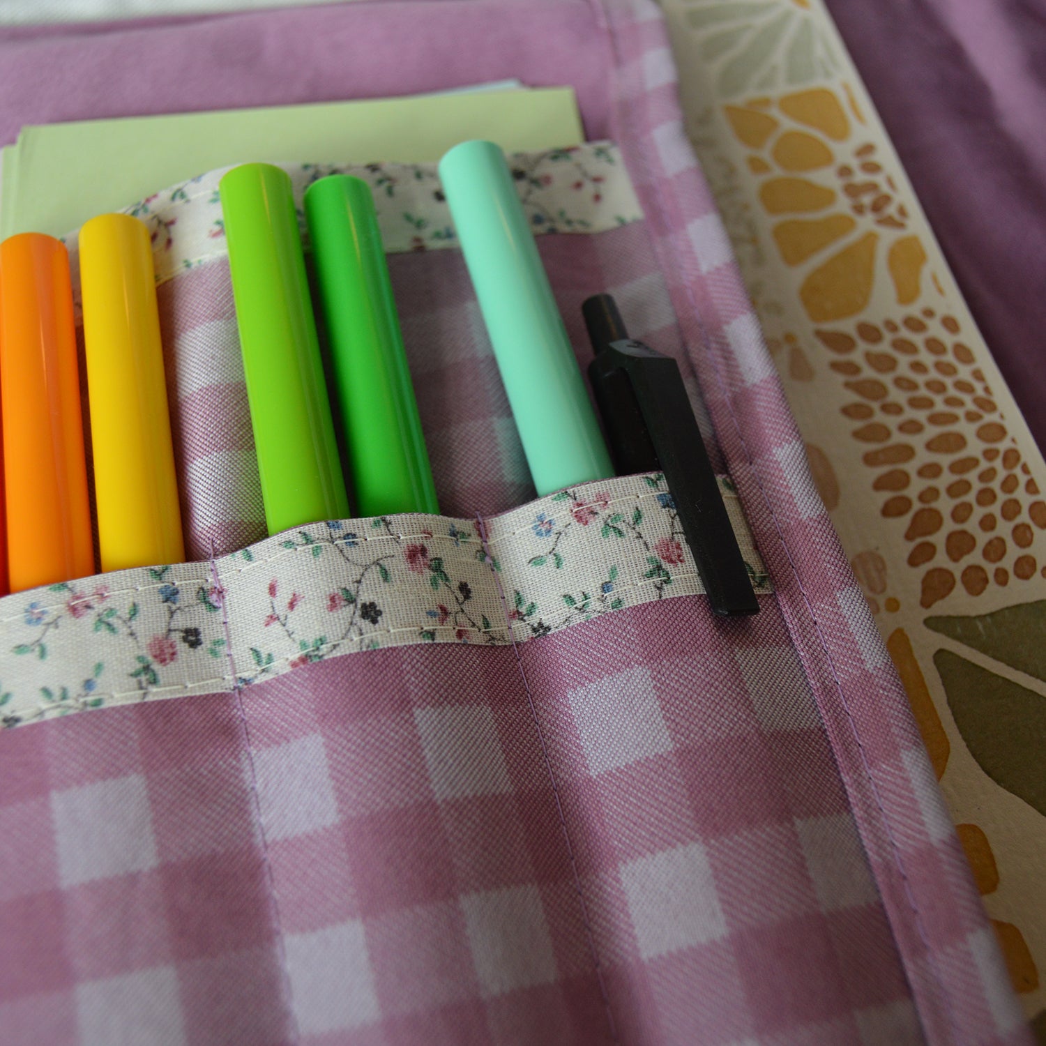 Set of colorful markers in a purple checkered fabric holder