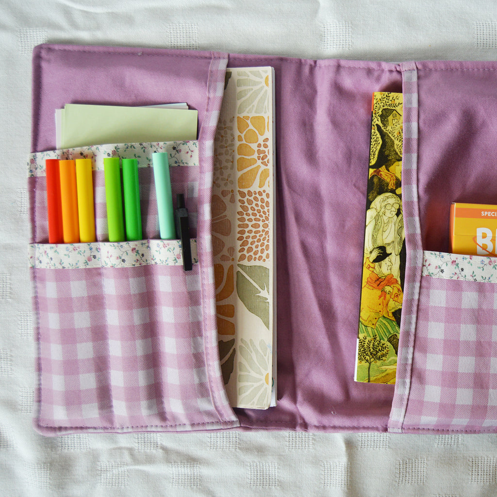 Purple fabric pouch organizer with stationery items on a white background