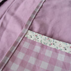 Close-up of a purple fabric pouch with a floral trim and checkered pattern.