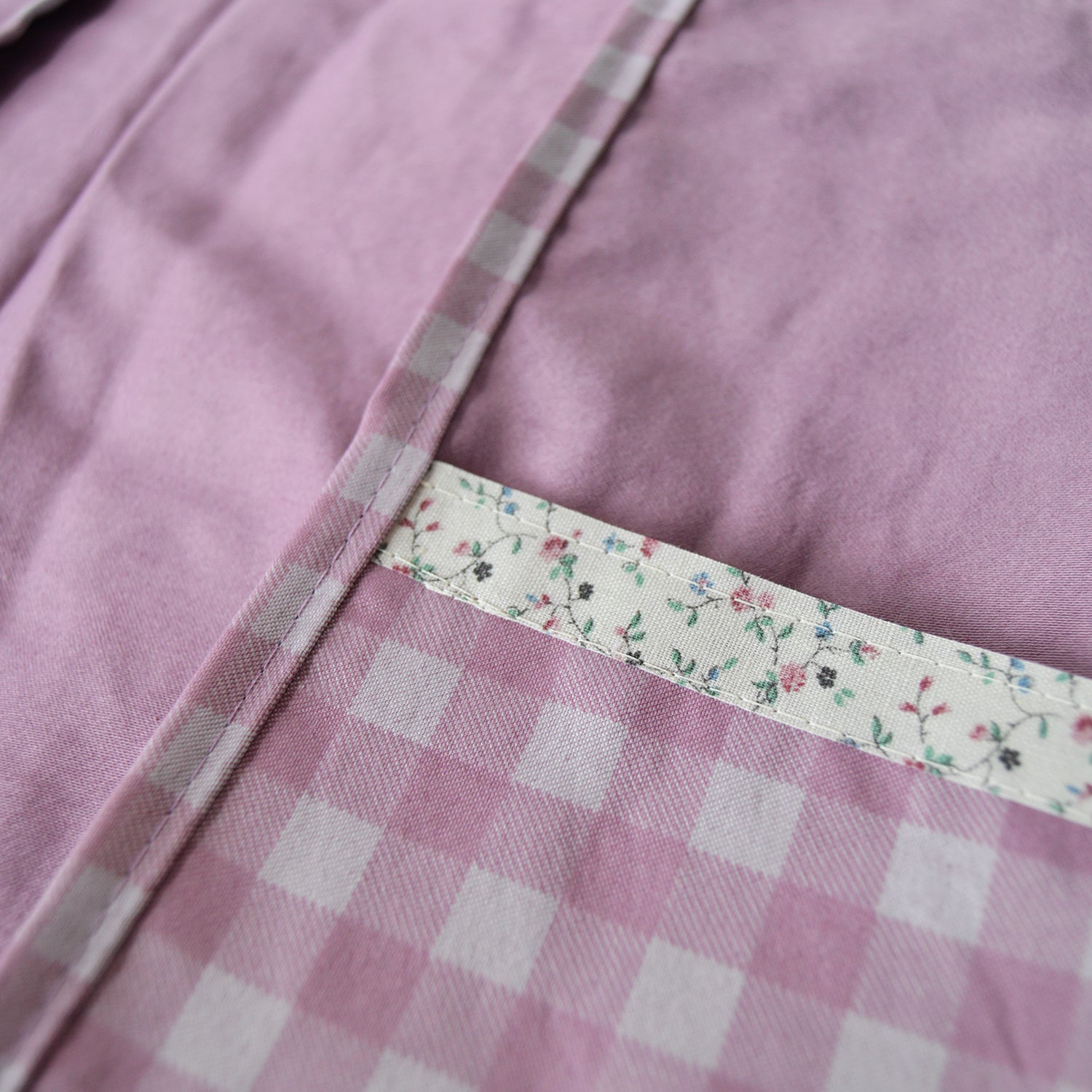 Close-up of a purple fabric pouch with a floral trim and checkered pattern.