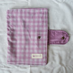 Purple checkered pouch with a brand label on a white fabric background