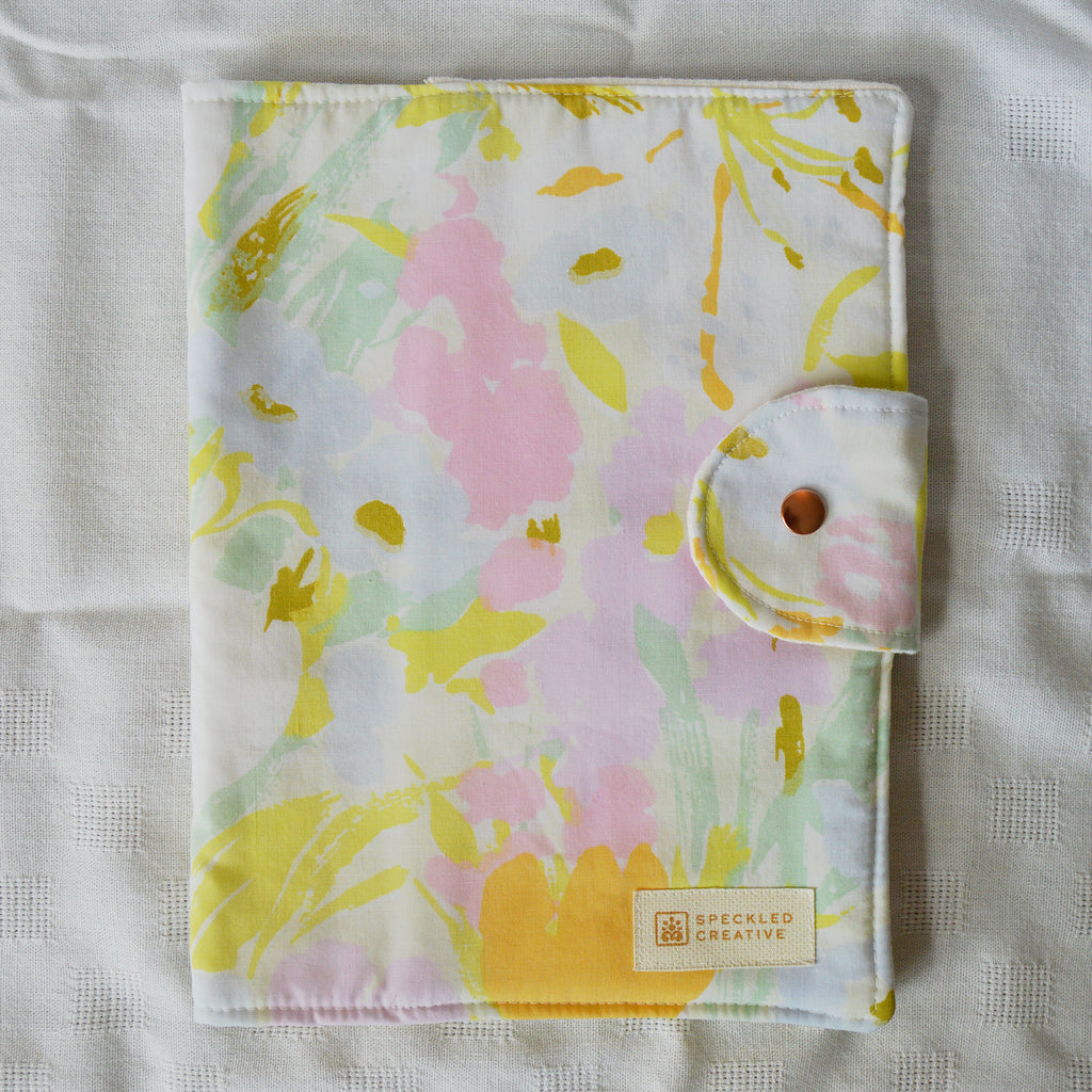 Floral patterned pouch with Speckled Creative label on a light fabric background