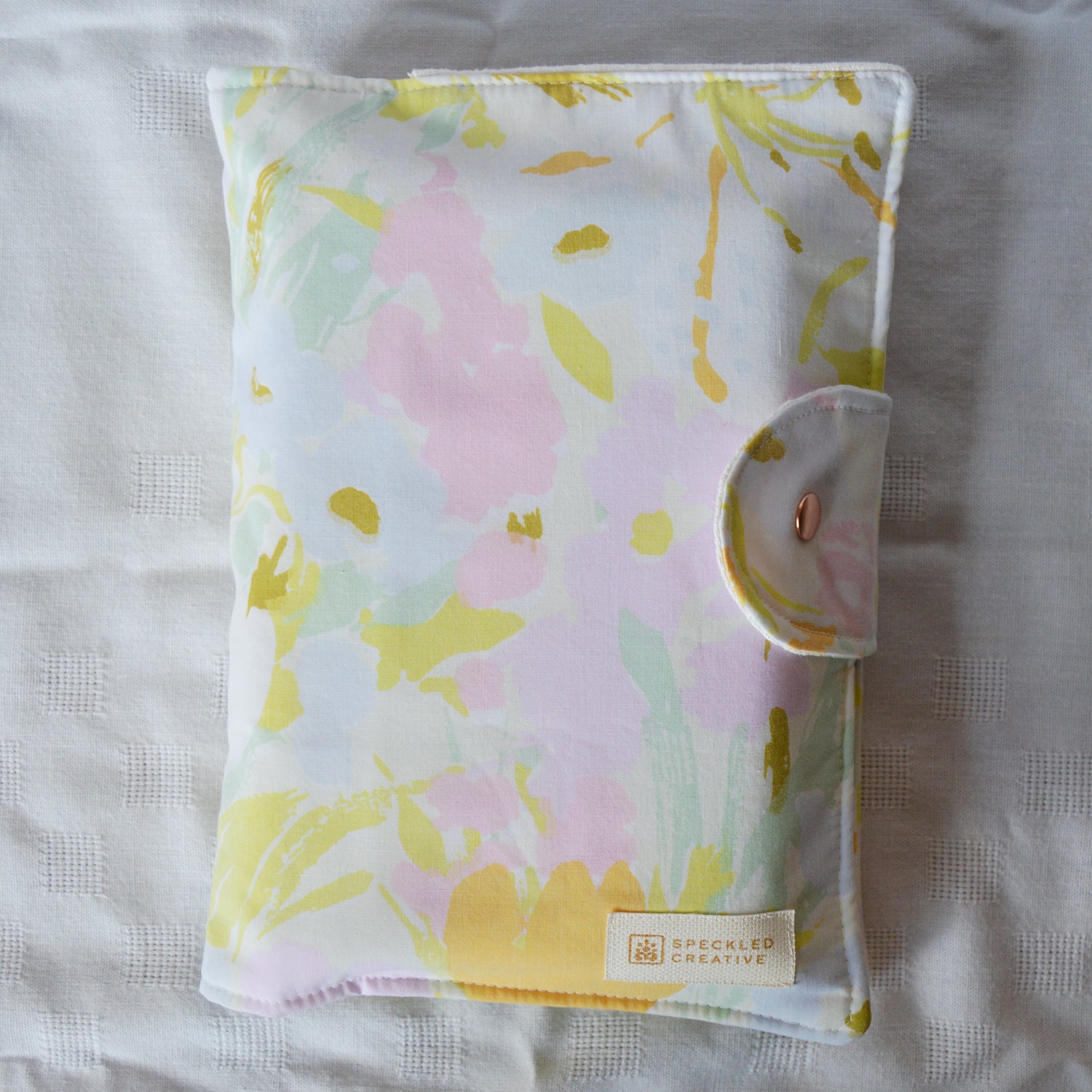 Floral patterned pouch with a brand label on a light background