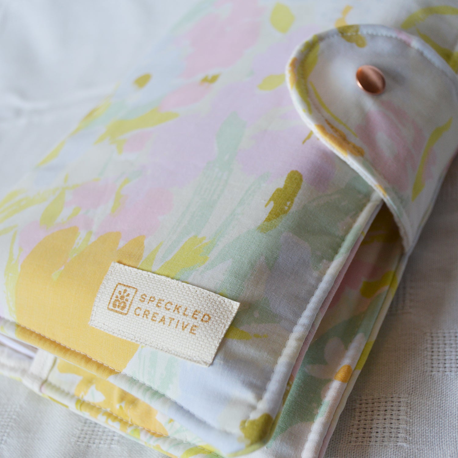 Floral patterned fabric pouch with Speckled Creative label on a white background