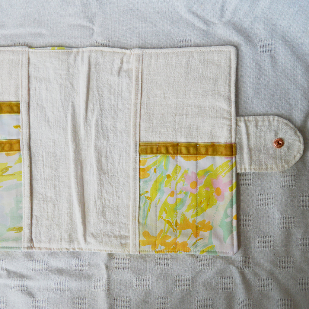 Floral patterned pouch with a button on a light gray background