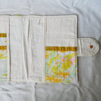 Floral patterned pouch with a button on a light gray background