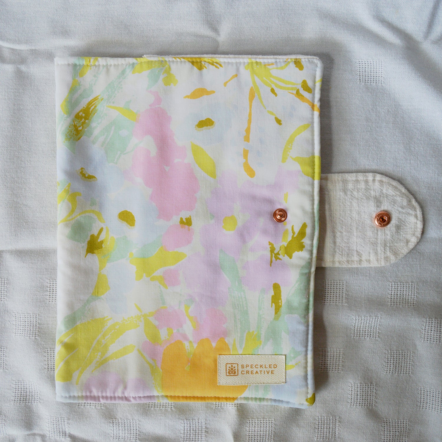 Floral patterned pouch with a brand label on a textured surface