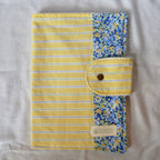 Yellow striped and floral patterned pouch with a button closure on a textured surface