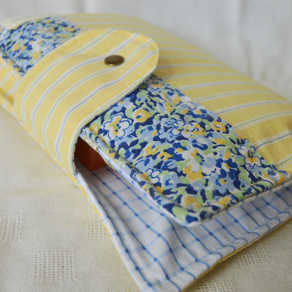 Folded fabric pouch with yellow and blue patterns on a beige surface