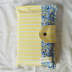 Folded yellow and blue patterned fabric pouch with a button on a white background
