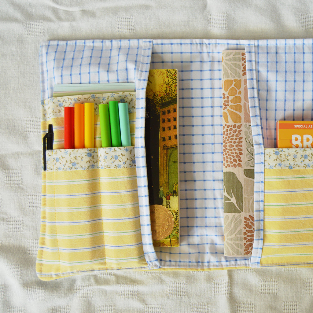 Fabric book sleeve with colorful pens and books on a textured surface