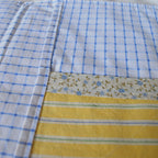 Close-up of the inside of a fabric pouch with blue checkered, floral border, and yellow striped patterns.