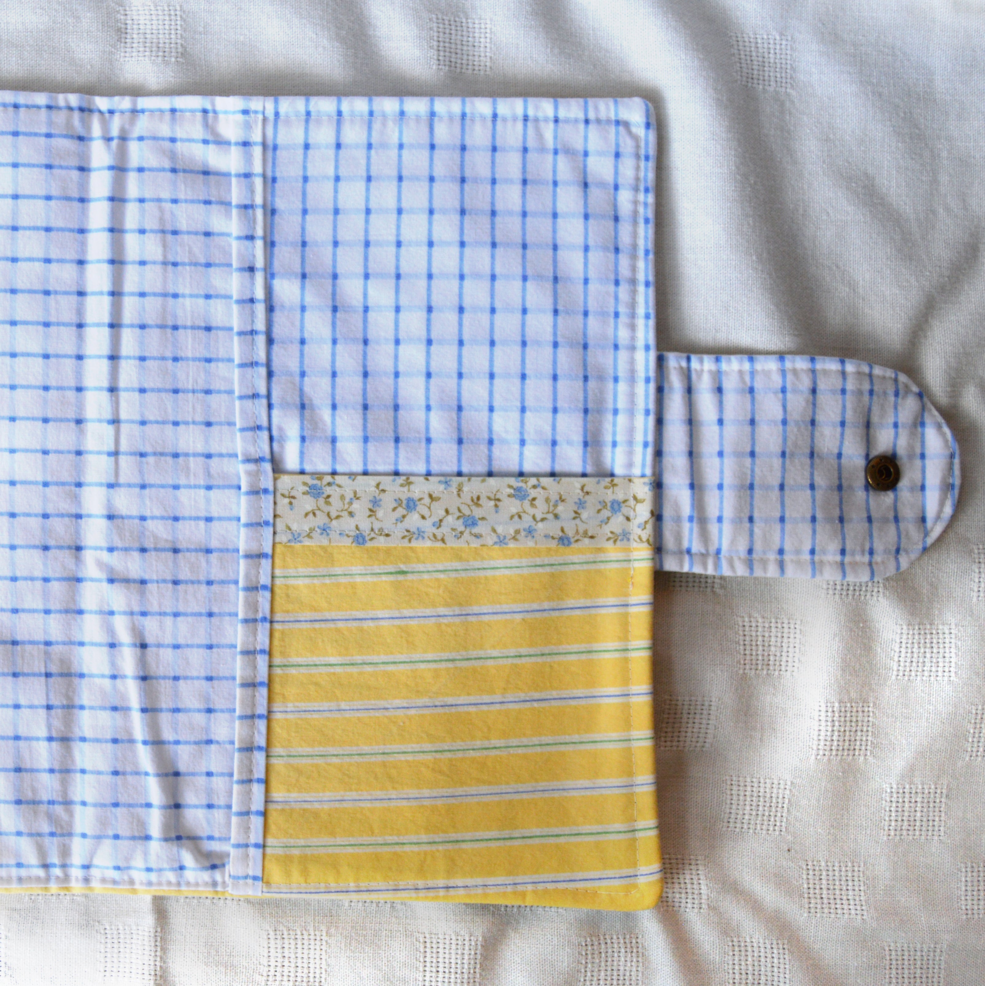Blue checkered, floral patterned, and yellow striped sections of the inside of a pouch on a white background