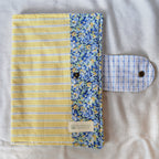 Yellow striped pouch with a floral border on a textured surface