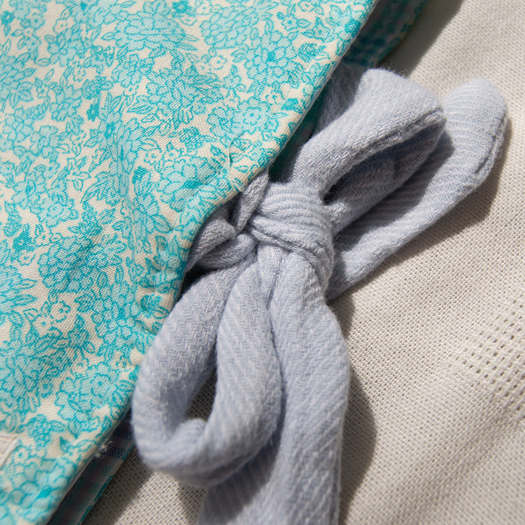 Close up on a light blue linen tie closure for a blue floral e-reader sleeve