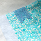 Close-up of a blue and white floral patterned fabric e-reader sleeve  with a blue bookmark appliqué