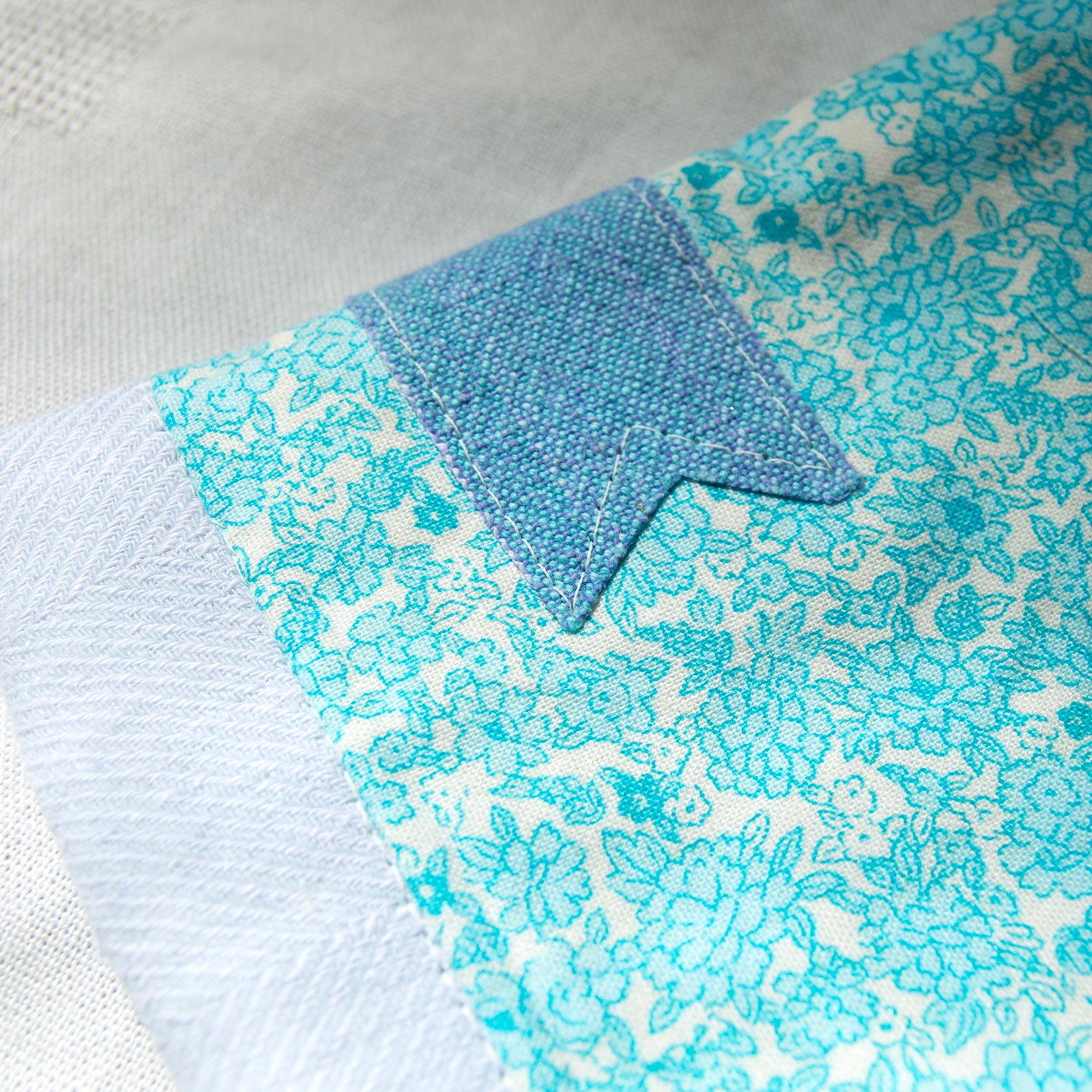 Close-up of a blue and white floral patterned fabric e-reader sleeve  with a blue bookmark appliqué