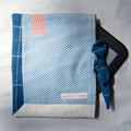 Fabric e-reader sleeve with blue and white polka-dot pattern with a tie closure and a red bookmark appliqué
