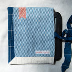 Sewn e-reader pouch with blue polka dot fabric with a pink bookmark appliqué on a white background