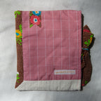 Pink checkered fabric e-reader sleeve with floral and polka dot borders on a light gray background