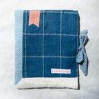 Blue checkered fabric e-reader sleeve with polka dot accents and a brand label on a white background