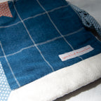 Blue and white checkered fabric e-reader pouch with a brand label on a gray background