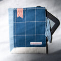 Blue checkered e-reader pouch with a pink bookmark appliqué on a white background