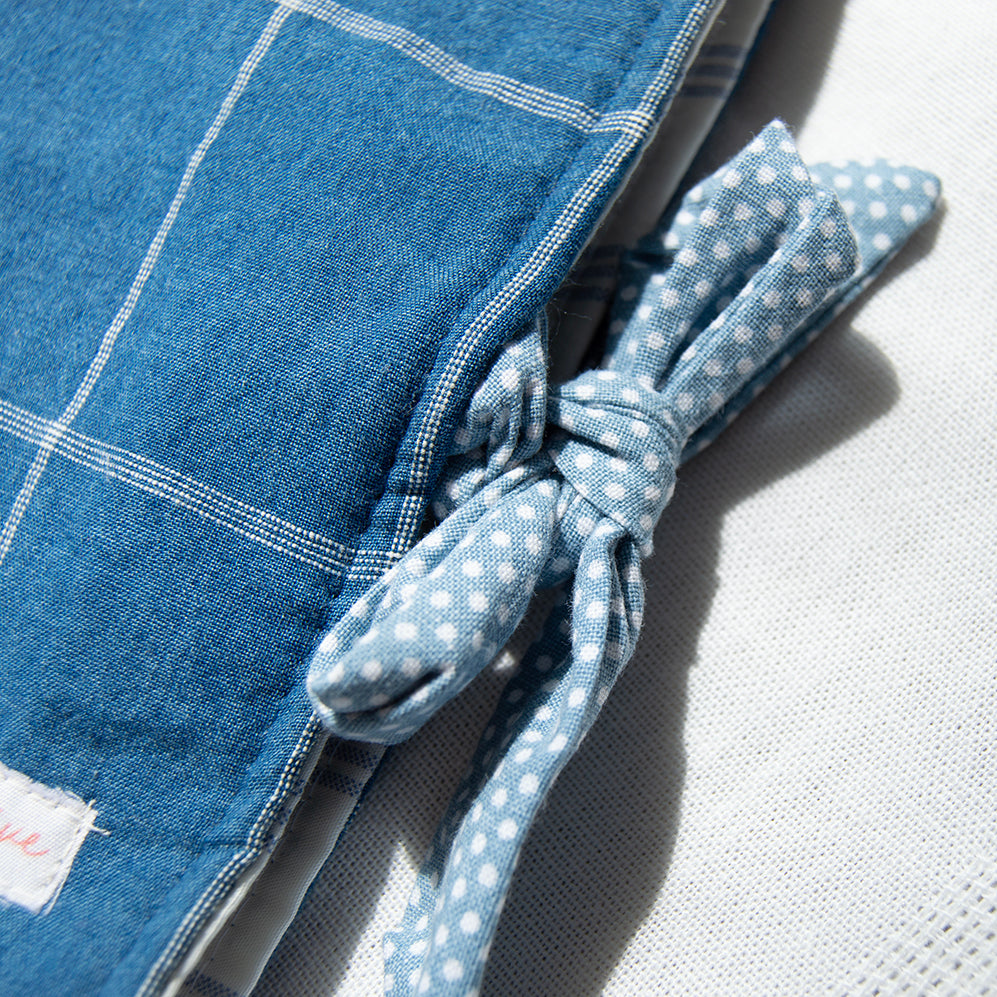 Blue checkered fabric e-reader sleeve with a polka dot fabric tie closure on a light background