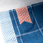 Close-up of e-reader sleeve with polka dots, floral pattern bookmark appliqué, and blue checkered design.