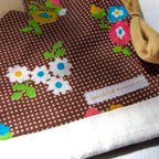 Brown fabric pouch with floral patterns and a visible brand label on a white background