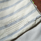 Label on a piece of fabric with blue stripes, featuring text about recycled product.