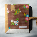 Floral-patterned fabric e-reader pouch with a visible brand label and a goldbookmark appliqué on a light gray background