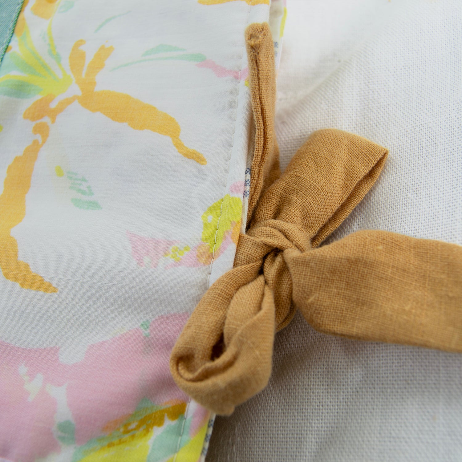 Close-up of a fabric e-reader sleeve with a floral pattern and a knotted gold ribbon.