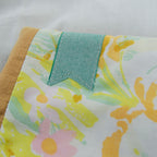 Floral patterned fabric e-reader sleeve with a teal bookmark appliqué on a white background
