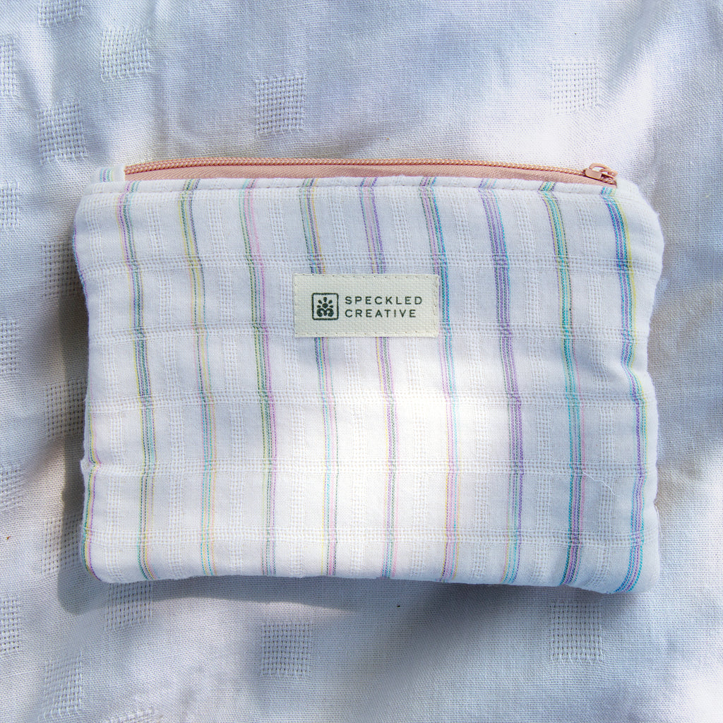 Striped pouch with a visible brand label on a textured fabric background