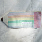 Multicolored striped pouch shaped like a pencil with a checkered eraser on a textured surface