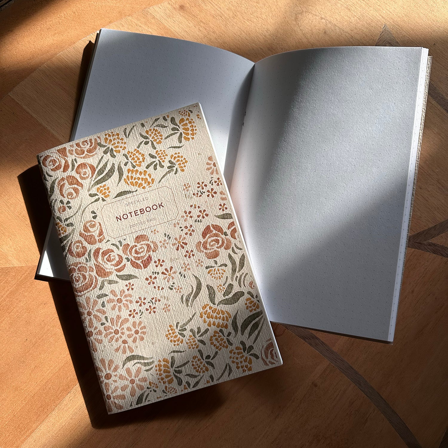 Notebook with floral pattern on wood surface.