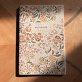 notebook with floral pattern on wooden surface.